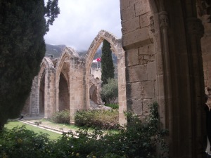 The ruins of Bellapais Abbey, Northern Cyprus with Turkish and Turkish Cypriot flags visible through the arch